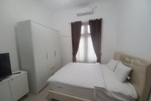 een kleine slaapkamer met een bed en een televisie bij OYO 93820 Salma Homestay Syariah in Purwokerto