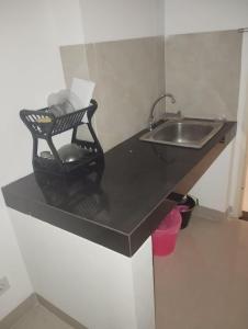 een keuken met een wastafel en een zwart aanrecht bij OYO 93826 Cprc Inn Serpong in Tangerang