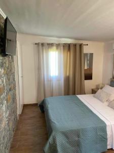 a bedroom with a bed and a window with a television at MANOLIS COTTAGE THANOS in Thános
