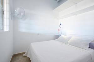 a white bedroom with a white bed and a window at El Gachero in Puerto de Mazarrón