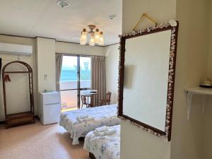 a bedroom with a mirror and a bed and a table at ビーチサイドペンションみーばる in Nanjo