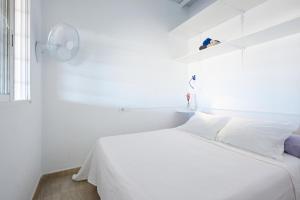 a white bedroom with a white bed and a window at Playa in Puerto de Mazarrón