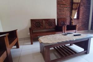 een woonkamer met een houten tafel en stoelen bij OYO 93839 Aquenda Homestay in Yogyakarta