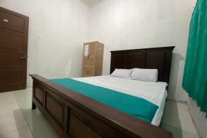 una camera con un grande letto con testiera in legno di OYO 93839 Aquenda Homestay a Yogyakarta