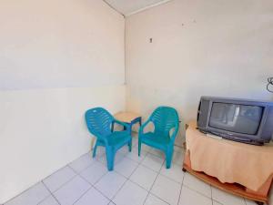 duas cadeiras azuis sentadas ao lado de uma mesa e uma televisão em SPOT ON 93840 Guest House Amanda Syariah em Bandar Lampung