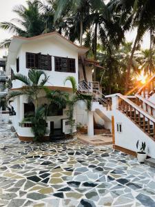 a house with palm trees and a tiled floor at Bayou Homestay and backwaters in Goa