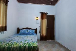 Schlafzimmer mit einem Bett, einem Fenster und einer Tür in der Unterkunft Capital O 93842 Jowo Segoro Resort in Yogyakarta