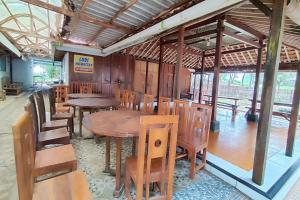una sala da pranzo con tavoli e sedie in legno di Capital O 93842 Jowo Segoro Resort a Yogyakarta