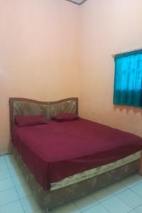 Un dormitorio con una cama con sábanas moradas y una ventana en SPOT ON 93852 Fermansio Homestay 2, en Medan