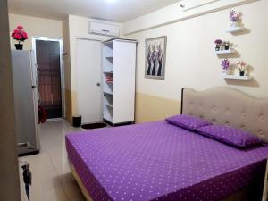 OYO 93857 Apartemen Kalibata City By Artomoro في جاكرتا: غرفة نوم مع سرير أرجواني مع لحاف أرجواني