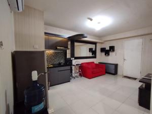OYO 93857 Apartemen Kalibata City By Artomoro في جاكرتا: مطبخ وغرفة معيشة مع أريكة حمراء