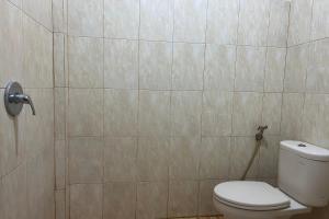 baño con aseo y pared de azulejos en OYO 93858 Kost Reski 2, 