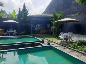a swimming pool with a table and an umbrella at OYO 93860 Wonosobo Bunkbed in Wonosobo