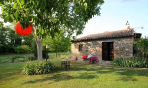 una pequeña casa de piedra en un patio con un árbol en Agriturismo Le Spighe, en Proceno