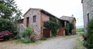 an old brick building with a gate and flowers at Agriturismo Le Spighe in Proceno