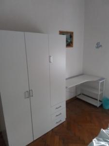 a white bedroom with a white cabinet and wooden floors at Appartament holidays Sistiana in Sistiana