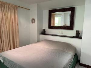 Dormitorio pequeño con cama y espejo en Bungalow Sarraméa en Sarraméa