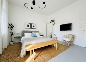 a white bedroom with a bed and a chair at Jardin Rooms in Split