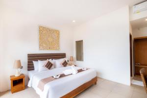 a white bedroom with a large bed and a table at AMP Beach House in Nusa Penida