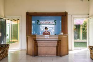 a man standing at a counter in a lobby at Hotel Plampitan in Semarang