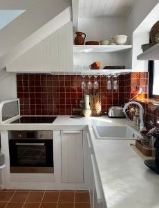 uma cozinha com armários brancos, um lavatório e azulejos vermelhos em Bergerie casitas suite em Canet-en-Roussillon