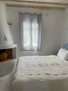 a white bedroom with a bed and a window at Mykonian 4 Bd Ocean Dream House in Agios Sostis in Agios Sostis Mykonos