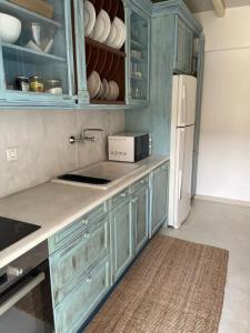 una cucina con armadi blu e frigorifero bianco di Mykonian 4 Bd Ocean Dream House in Agios Sostis ad Agios Sostis Mykonos