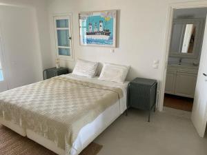 a white bedroom with a bed and two windows at Mykonian 4 Bd Ocean Dream House in Agios Sostis in Agios Sostis Mykonos