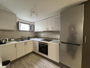 uma cozinha com armários brancos e um frigorífico de aço inoxidável em Emporio New Classic 1Bd Santorini Stylish Apt em Emporio