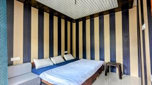 Cama en habitación con pared a rayas en Triyugi Heights cottage sitapur, en Trijugi Nārāyan