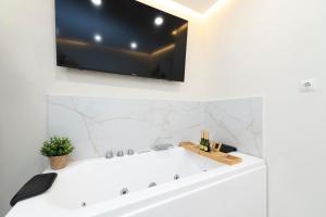 a bathroom with a white tub with a tv on the wall at EXCLUSIVE APARTMENT JACUZZi in Málaga