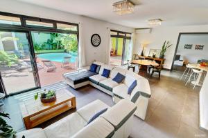 a living room with white furniture and a pool at La Villa du Patio Parenthèse familiale Piscine 4 in Saint-Pierre