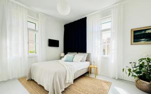 a white bedroom with a bed and two windows at Jardin Rooms in Split
