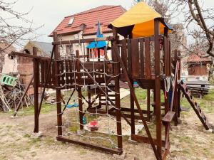um jogo de madeira com um parque infantil em frente a uma casa em Leaganul Bucovinei Guest House em Suceava