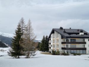 a building in the snow with trees and mountains at Holiday flat for skiing couples Triangel D - Parpan Lenzerheide in Parpan