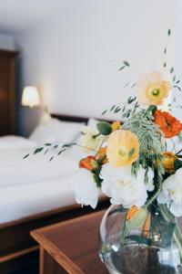 un jarrón lleno de flores en una mesa junto a una cama en Hotel Reindl Suiten & Appartments en Bad Füssing