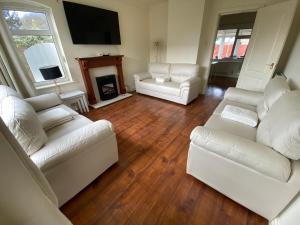uma sala de estar com sofás brancos e uma lareira em Spacious 3 Bed House in Penrhyn Bay Llandudno em Llandudno