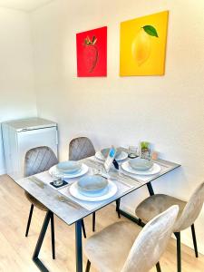 a table with chairs and plates and paintings on the wall at Explore CH & FR - deluxe apartment Basel Airport in Herten