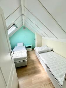 an attic room with two beds and a window at Zeepark Mercator in Wenduine