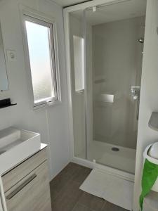 a bathroom with a shower and a sink and a window at Camping Le Lac des Rêves Lattes in Pérols