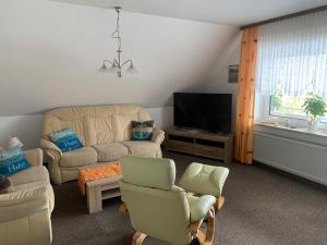 a living room with a couch and chairs and a tv at Haus-Sonneck in Esens