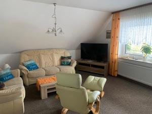 Una sala de estar con un sofá y sillas y un televisor. en Haus-Sonneck, en Esens