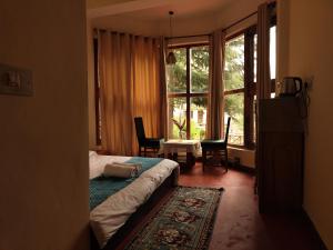 TSUKIMI Homestay, Naggar, Manali في Nagar: غرفة نوم بسرير ونافذة كبيرة