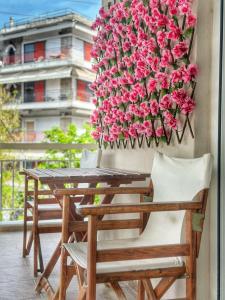 a table and chairs with pink flowers on a balcony at Psimithefto Luxury Apartments in Thessaloniki