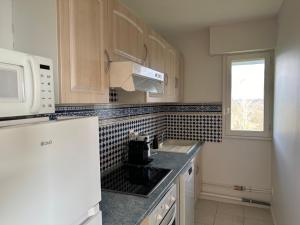 Una cocina con una pared de azulejos blancos y negros. en Appartement terrasse vue mer/campagne, en Blonville-sur-Mer 10 fotos más