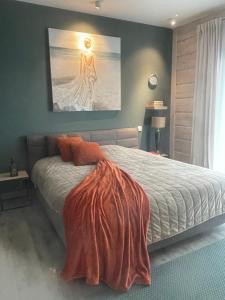 a bedroom with a bed with an orange blanket on it at Un petit îlot de confort - made in Finland in Monflanquin +24 photos