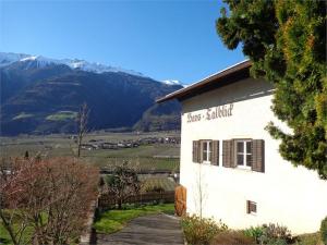 a white building with a sign that reads those smiling at Haus Talblick "Envy" Ferienwohnung in Naturno