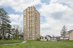 a tall building in a grassy field next to a building at STAYY Sky Studio near Limmattal Hospital - contactless check-in in Schlieren