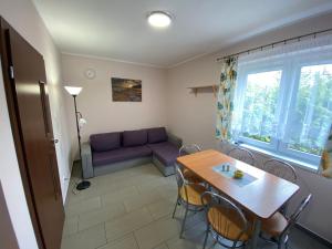 ein Wohnzimmer mit einem Tisch und einem lila Sofa in der Unterkunft Ptasi Raj in Karwia