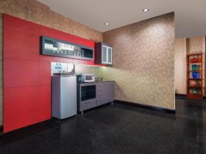 a kitchen with a refrigerator and a red wall at Manhattan Hotel Jakarta in Jakarta